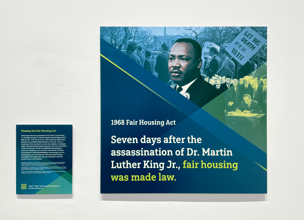 A collage of Martin Luther King Jr. on a gallery wall with a text panel explaining the signing of the Fair Housing Act to the left.