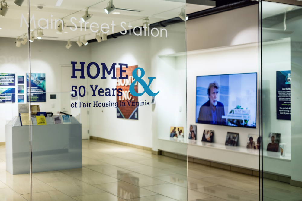 The glass doors of the Main Street Station gallery open to the "HOME and 50 Years of Fair Housing" exhibit.